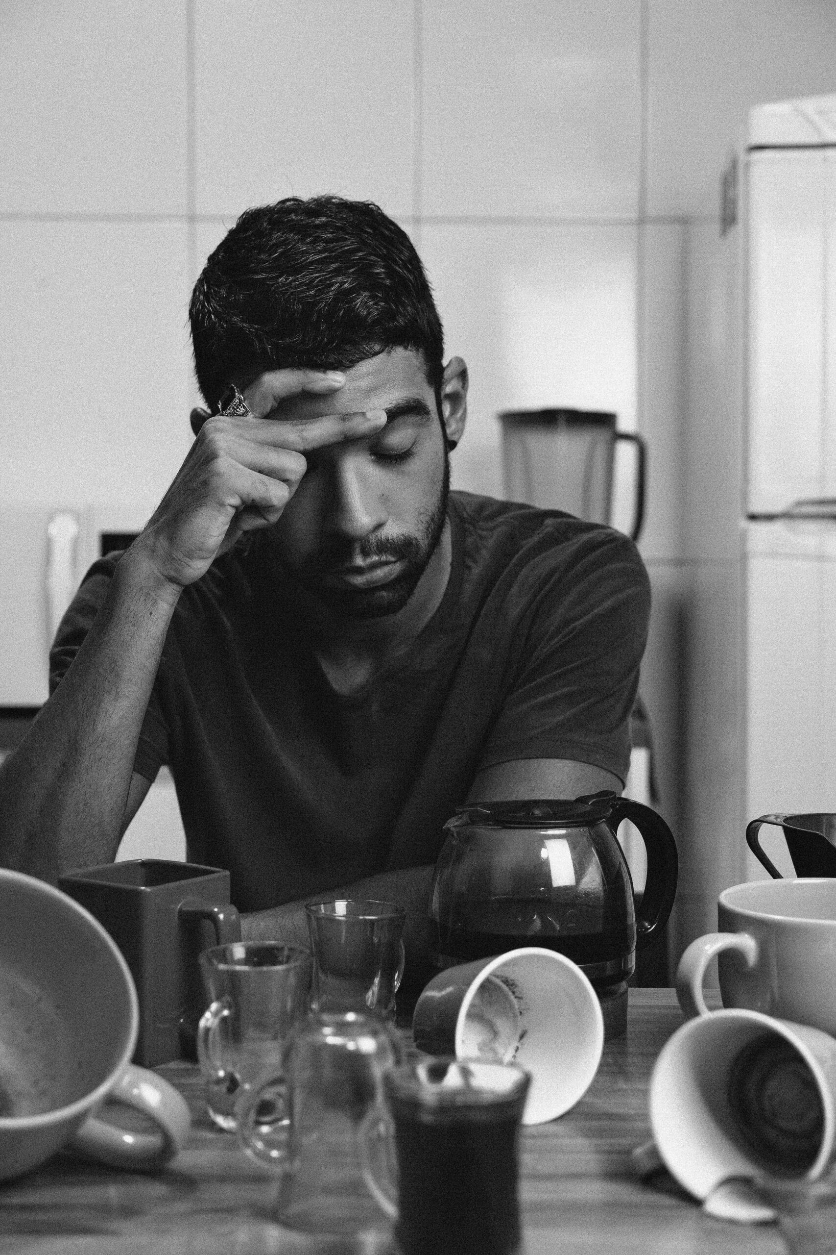 Man feeling tired and sleepy after eating a meal Tired man sitting at a table after eating, showing signs of post-meal sleepiness